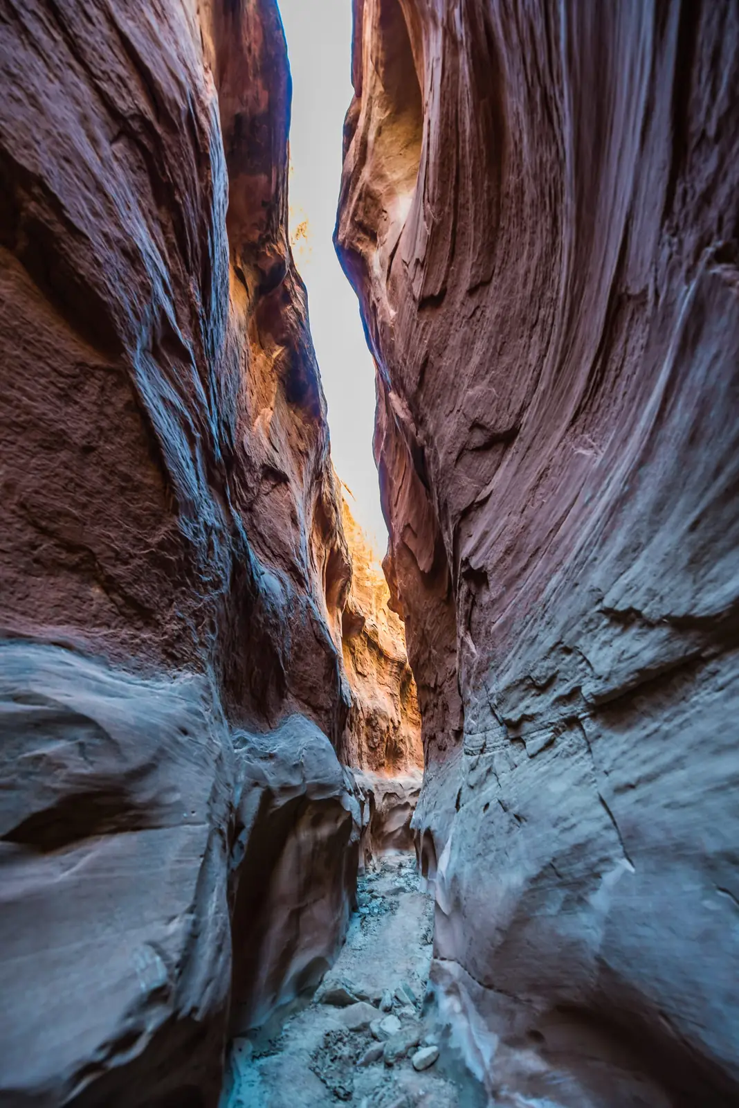 Narrow slot canyon with a sliver of light at the top