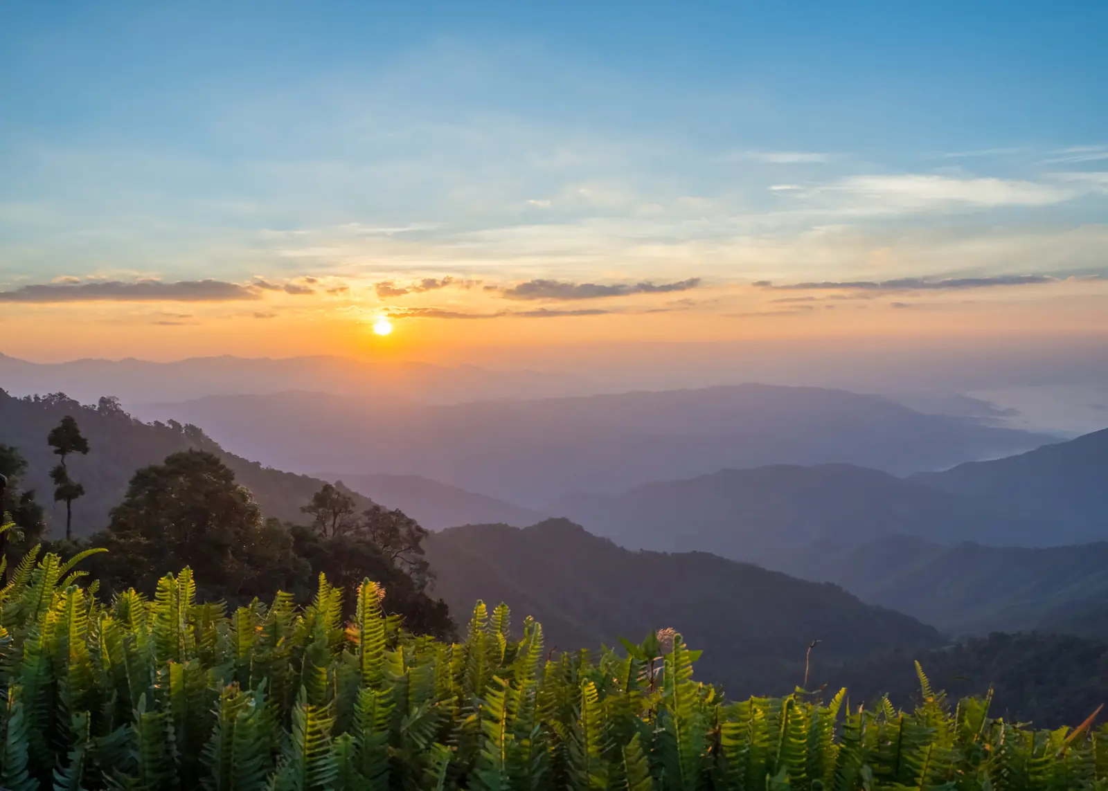Sunrise breaking over a layered mountain range